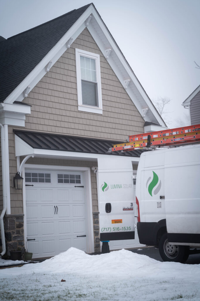 A Lumina Solar installer van in front of a single family home on a snowy foggy day