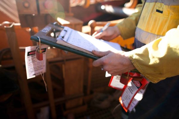 Construction site supervisor inspecting checking names list at safe task isolation procedure permit holder box to ensure all construction miners are locking on correct permit prior to work on site