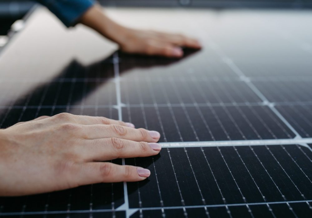 Close up of a woman touching solar panels on the roof.