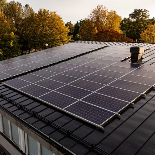 Aerial view of a house with roof solar cells, autumn forest background - drone shot